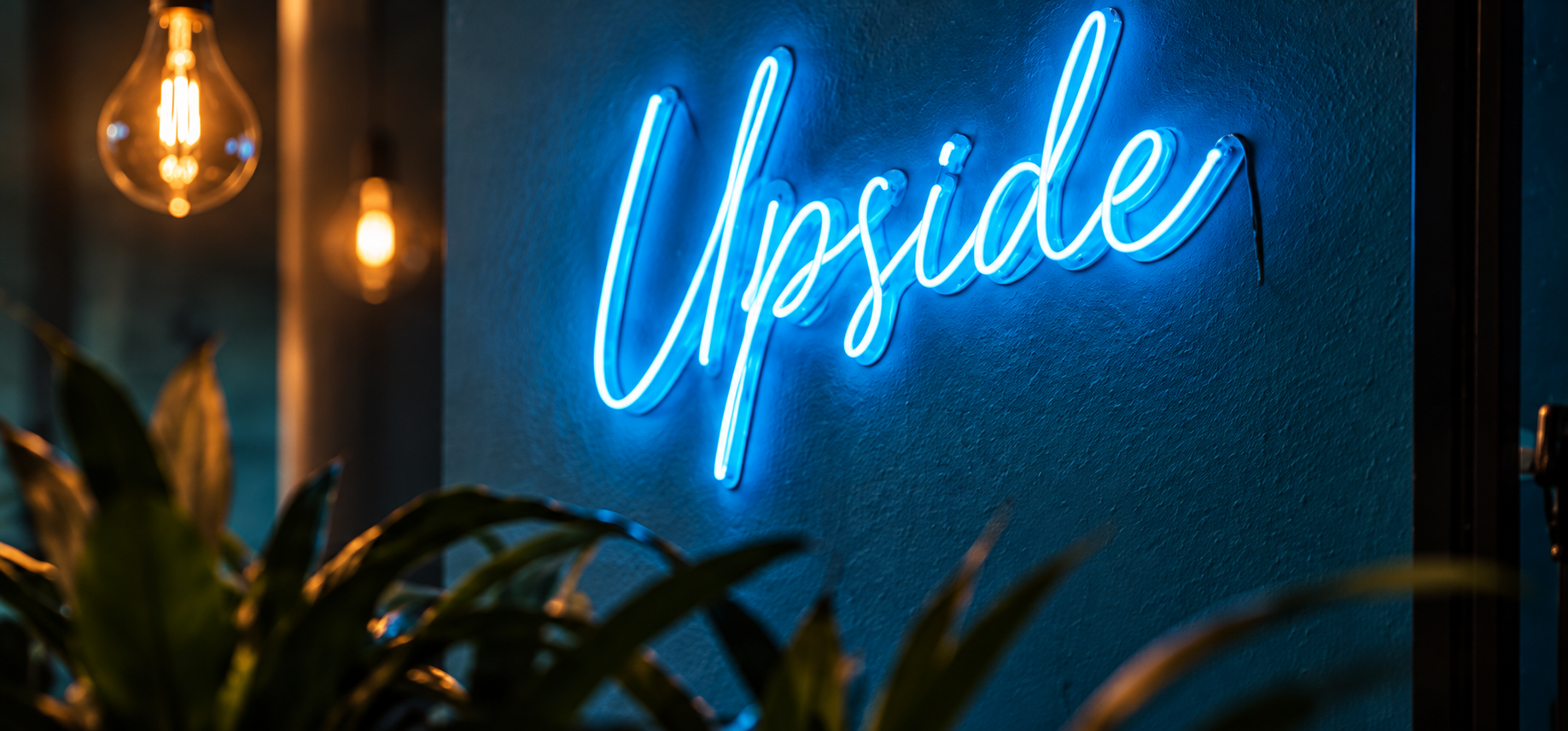 Enseigne lumineuse Upside sur un mur bleu